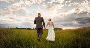 complete weddings couple walking through a field